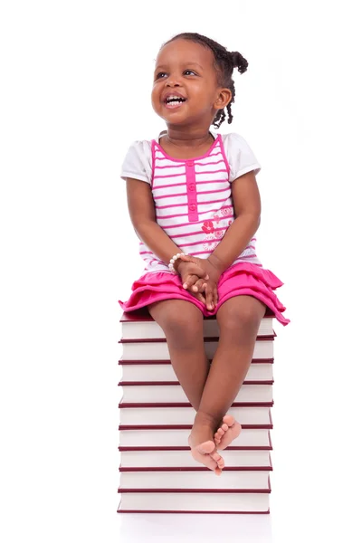 Cute black african american little girl seated in a stack of boo — Stock Photo, Image