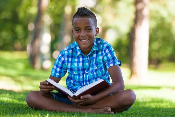 Outdoor portrait of student black boy reading a book - African p — Stock Photo, Image