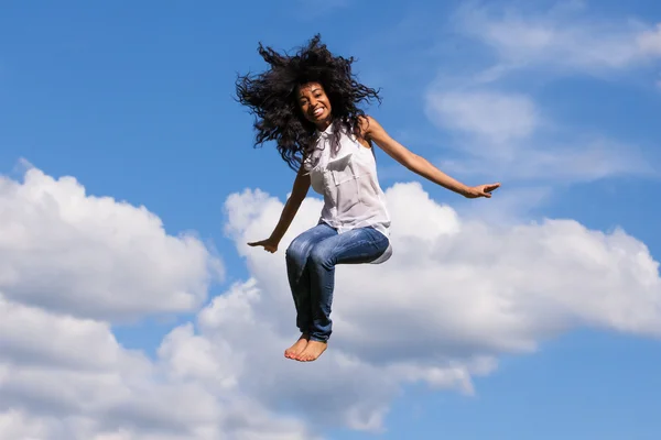 Außenporträt eines schwarzen Mädchens im Teenager-Alter, das über einen blauen Himmel springt — Stockfoto