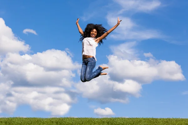 Außenporträt eines schwarzen Mädchens im Teenager-Alter, das über einen blauen Himmel springt — Stockfoto