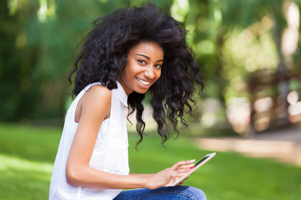 Outdoor portrait of a teenage black girl using a tactile tablet
