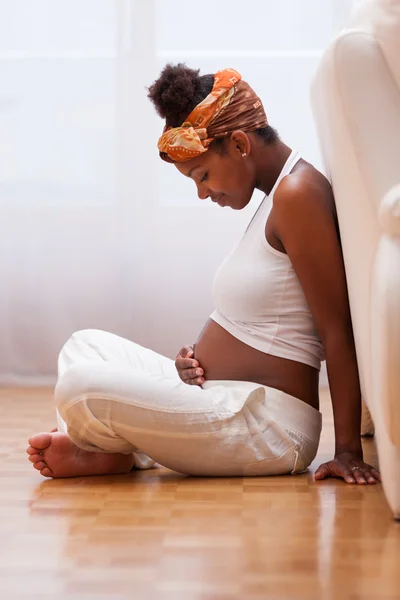 Mujer negra embarazada joven tocándose el vientre - gente africana —  Fotos de Stock
