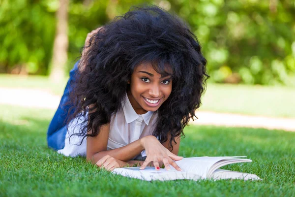 Νεαρός φοιτητής κορίτσι διαβάζοντας ένα βιβλίο στο πάρκο σχολείο - αφρικανική p — Φωτογραφία Αρχείου
