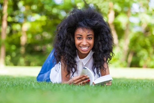 Young student girl reading a book in the school park - African p — Stock Photo, Image