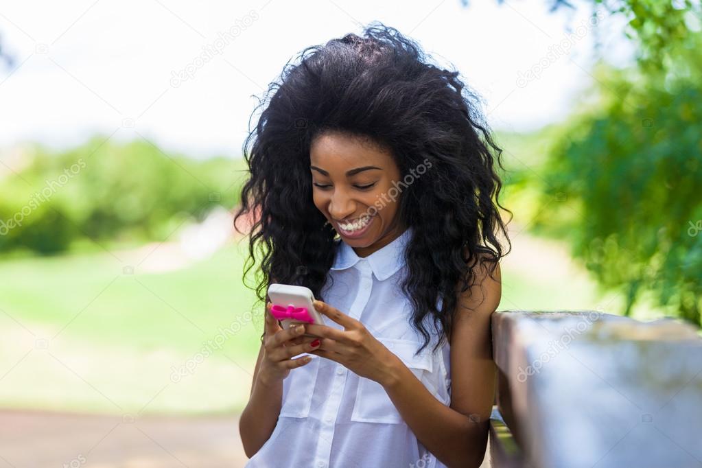 Outdoor portrait of a teenage black girl using a mobile phone -