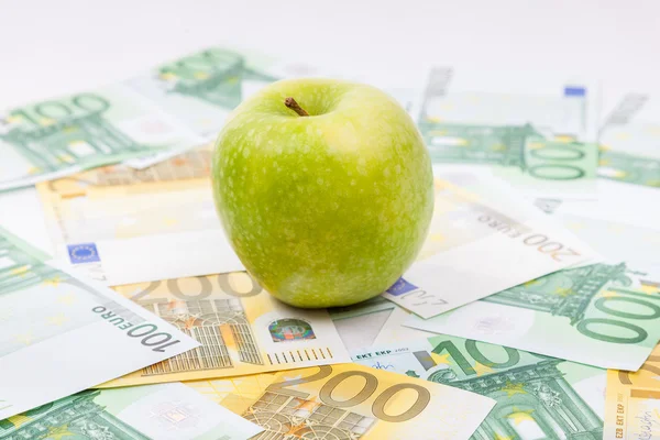 Manzana verde en billetes en euros esparcidos por el suelo - Europa — Foto de Stock