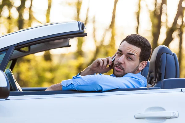 Joven conductor latinoamericano haciendo una llamada telefónica mientras conduce —  Fotos de Stock