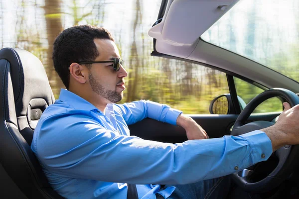 Junger schwarzer lateinamerikanischer Fahrer am Steuer seines neuen Autos — Stockfoto