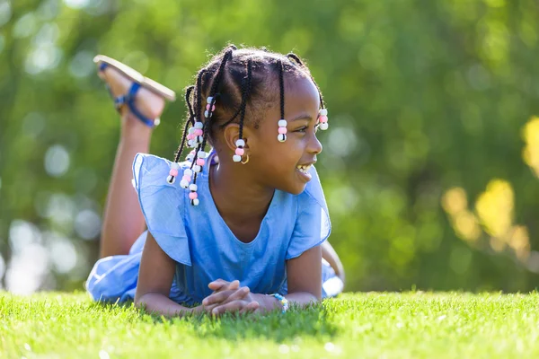 Retrato al aire libre de una linda joven negra acostada en la g — Foto de Stock