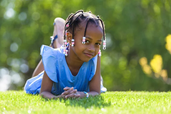Retrato ao ar livre de uma linda jovem garota negra deitada no g — Fotografia de Stock