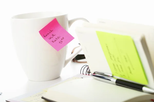 Office roze en gele kleverige nota over een kopje koffie — Stockfoto