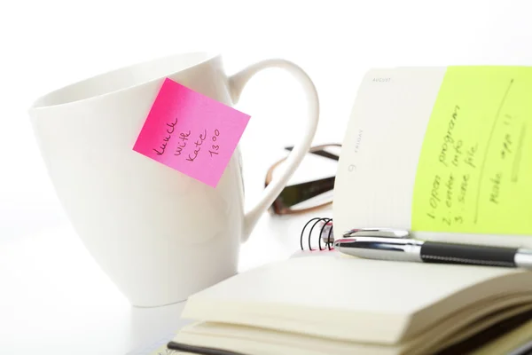 Office roze en gele kleverige nota over een kopje koffie — Stockfoto