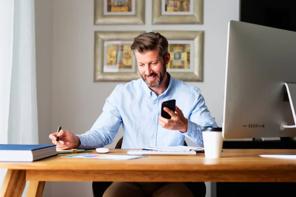 Homem Negócios Feliz Sentado Mesa Atrás Seu Computador Usando Telefone — Fotografia de Stock