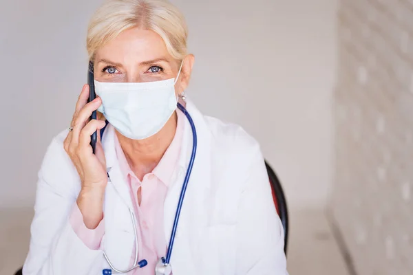 Senior Ärztin Trägt Gesichtsmaske Während Sie Hinter Ihrem Laptop Sitzt — Stockfoto