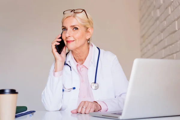 Médico Sonriente Sentado Escritorio Detrás Computadora Portátil Mientras Recibe Una — Foto de Stock