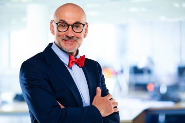 İş adamı takım elbise ve papyon giyer ve ofiste kollarını kavuşturur.. 