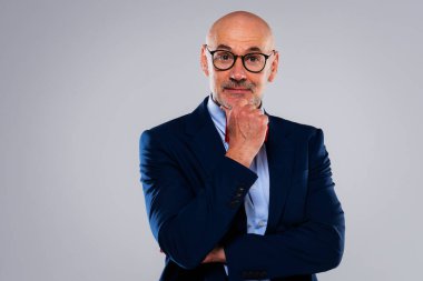 Gri arka planda elleri çenesinde duran bir iş adamı görüntüsü. Boşluğu kopyala.