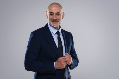 Gri arka planda dikilirken takım elbise ve kravat takan gülümseyen iş adamının görüntüsü. Boşluğu kopyala.