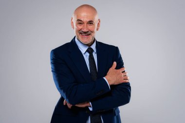 Gri arka planda dikilirken takım elbise ve kravat takan gülümseyen iş adamının görüntüsü. Boşluğu kopyala.