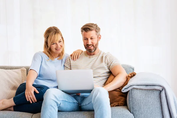 Pareja Feliz Sentada Sofá Casa Usando Ordenador Portátil Mientras Navega — Foto de Stock