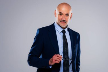 Gri arka planda dikilirken takım elbise ve kravat takan gülümseyen iş adamının görüntüsü. Boşluğu kopyala.