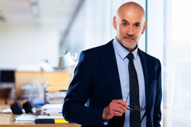 Ofiste dikilirken takım elbise ve kravat takan bir iş adamı.. 