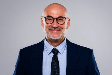 Gri arka planda dikilirken takım elbise ve kravat takan gülümseyen iş adamının görüntüsü. Boşluğu kopyala.