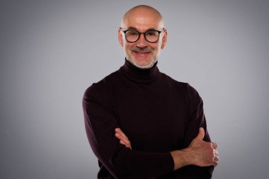 İzole edilmiş arka planda dikilirken gündelik kıyafetler giyen orta yaşlı yakışıklı bir adamın stüdyo portresi. 