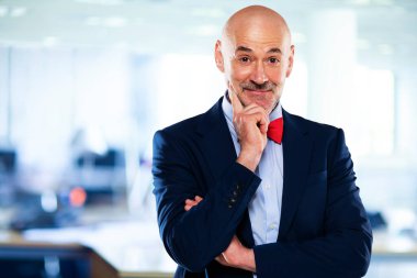 İş adamı takım elbise ve papyon giyer ve ofiste kollarını kavuşturur.. 