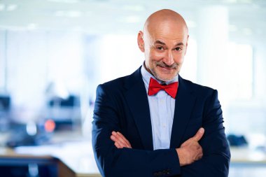 İş adamı takım elbise ve papyon giyer ve ofiste kollarını kavuşturur.. 