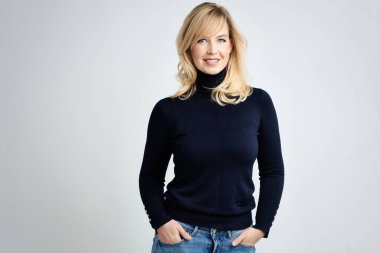 Çekici sarı saçlı, balıkçı yaka kazak giyen bir kadının stüdyo portresi.. 