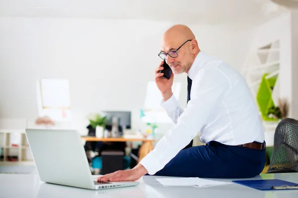 Pewny Siebie Biznesmen Telefon Korzystania Laptopa Podczas Siedzenia Biurze Pracy — Zdjęcie stockowe