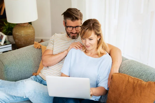 Casal Feliz Sentado Sofá Casa Usando Laptop Enquanto Navega Web — Fotografia de Stock