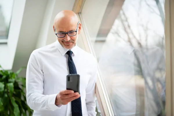 Retrato Hombre Mediana Edad Sonriente Parado Ventana Mientras Envía Mensajes —  Fotos de Stock