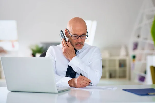 Pewny Siebie Biznesmen Telefon Korzystania Laptopa Podczas Siedzenia Biurze Pracy — Zdjęcie stockowe