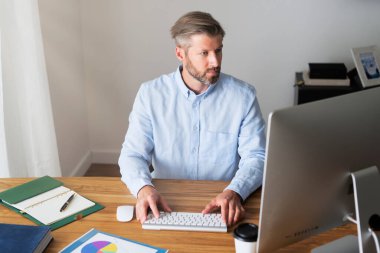 İş adamı evde çalışırken bilgisayarının arkasında masasında oturuyor. Merkez Ofis. 