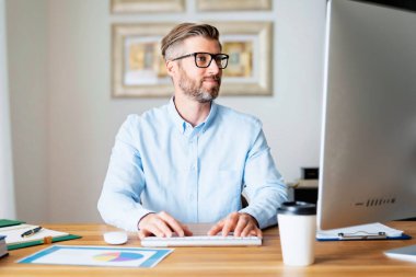 İş adamı evde çalışırken bilgisayarının arkasında masasında oturuyor. Merkez Ofis. 