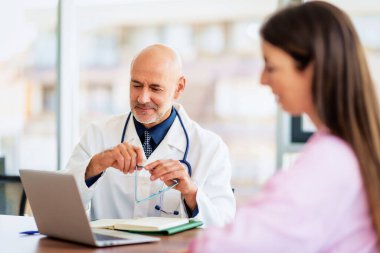 Shot of a male doctor sitting in a doctor's office listening to a female patient while she explains her symptoms and consults.