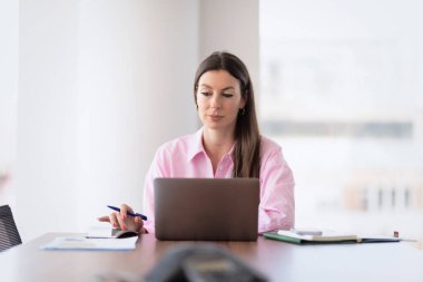 Shot of a financial assistant businesswoman working on laptop and using calculator while working at the office. 