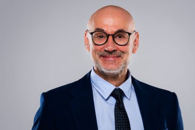 Close-up of smiling businessman wearing suit and eyewear while standing at isolated grey background. Copy spcace.