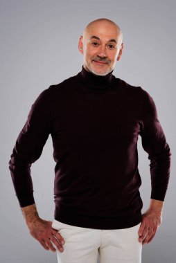 Studio portrait of handsome middle aged man wearing casual clothes while standing at isolated grey background. Copy space. 