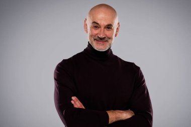 Studio portrait of handsome middle aged man wearing casual clothes while standing at isolated grey background. Copy space. 