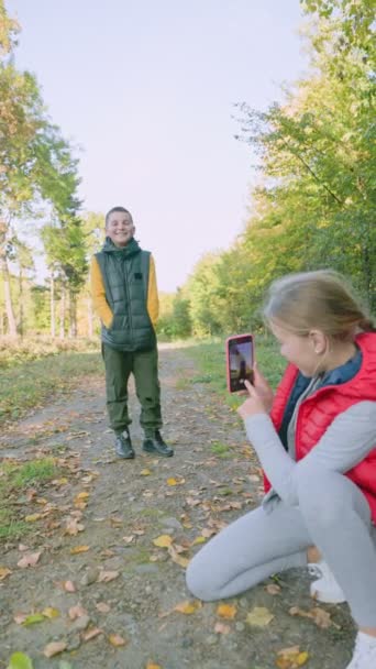 Девушка фотографирует мальчика по телефону — стоковое видео