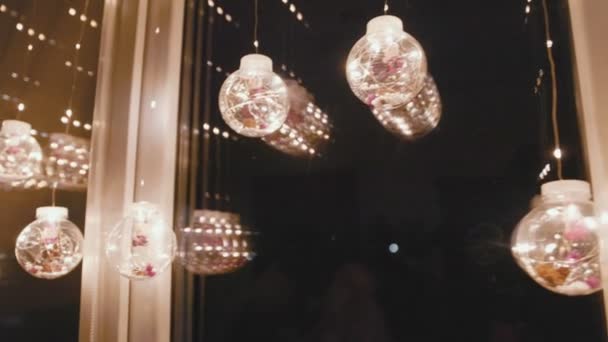Светящиеся гирлянды в виде шариков на окне — стоковое видео