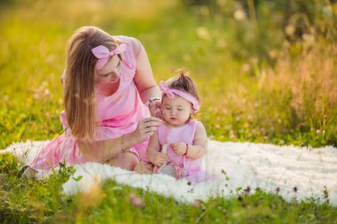 Anne ve kızı battaniyenin üzerinde oturuyorlar.