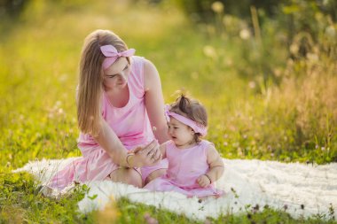 Anne ve kızı battaniyenin üzerinde oturuyorlar.