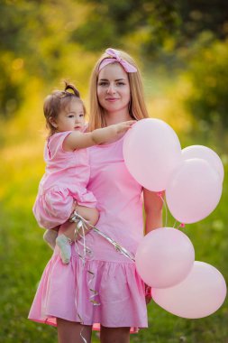 Anne kızı ve ellerinde balonlarla.