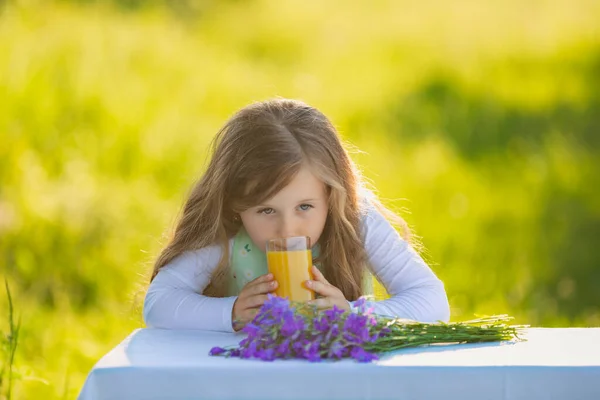 Girl drinking juice sitting at the table — Stock Photo, Image