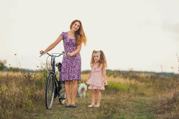 Mother and daughter walking with a bicycle and a dog — Stock Photo, Image