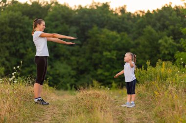 Anne ve kızı doğa egzersiz yaparak